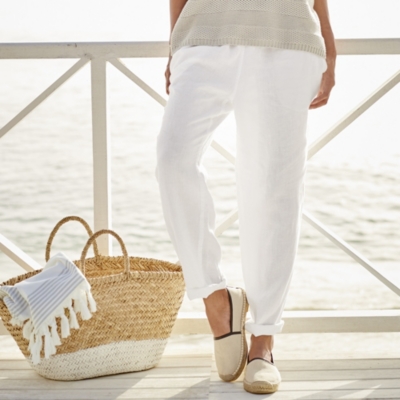 Woman wearing white linen beach pants.